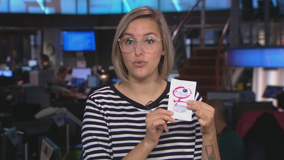 Une femme blonde tient une pochette qui contient un condom féminin.