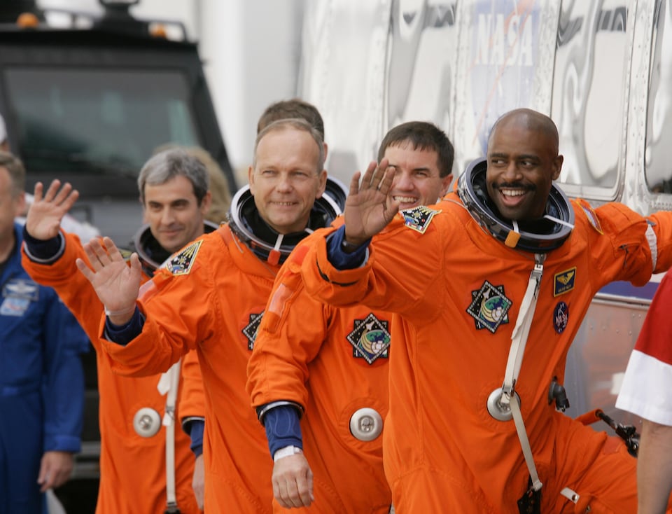 Cinq astronautes en costumes orange. 