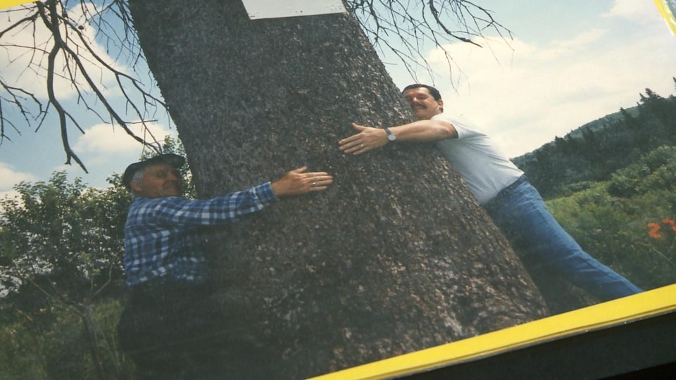 Léonard Otis et un autre homme enlacent un arbre.