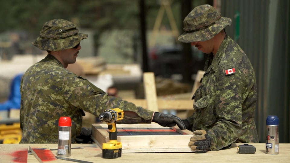 Deux soldats canadiens préparent le campement sur la base militaire en Lettonie.
