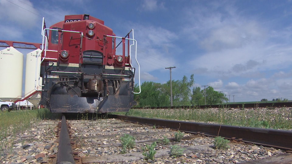 Une locomotive rouge, vue de devant, stationnée sur la voie ferrée. 
