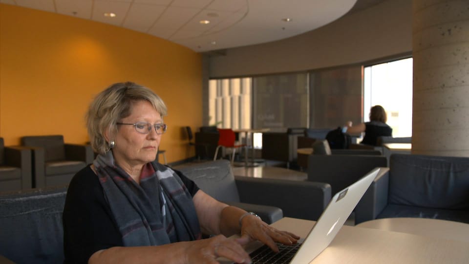 On voit Mme Vandelac qui travaille à l'ordinateur.