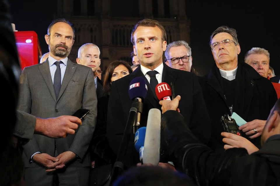 Le président français Emmanuel Macron, avec à ses côtés le premier ministre Édouard Philippe et l'archevêque de Paris Michel Aupetit, tient un point de presse près de la cathédrale Notre-Dame de Paris.