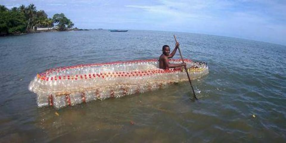 Au Cameroun, à Douala, un jeune homme vogue sur l'un des bateaux qu'il a conçus à partir de bouteilles en plastique recyclé. 