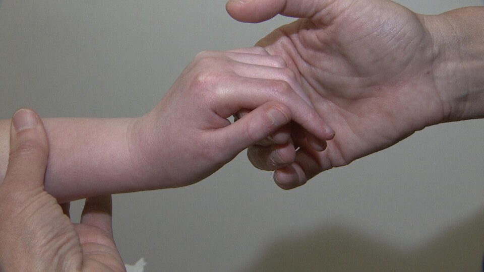 Gros plan sur les mains de la médecin qui tient la main d'une petite fille