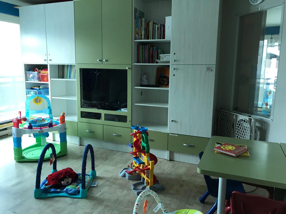 Des jouets pour enfants jonchent le sol de la salle de jeux, munie de grandes armoires et d'une télévision.