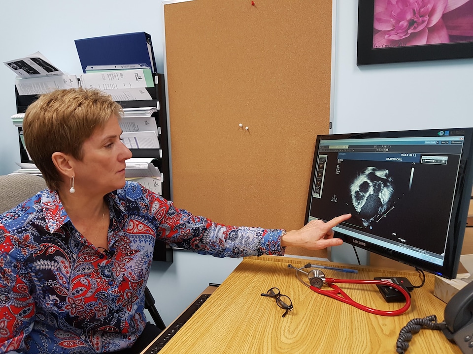 Une médecin montre l'échographie d'un coeur sur un écran d'ordinateur. 