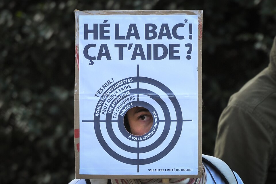 Un manifestant porte une cible de tir sur laquelle on peut lire : « Hé la BAC, ça t'aide? »