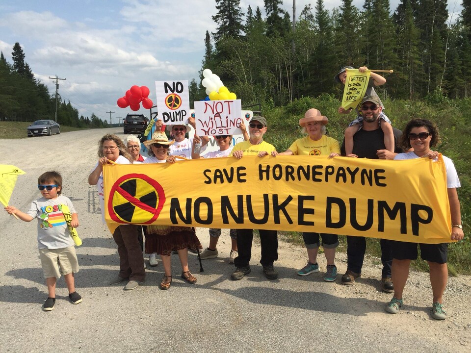 Des manifestants tenant une banderole sur laquelle est écrit : « Save Hornepayne - No Nuke Dump ».