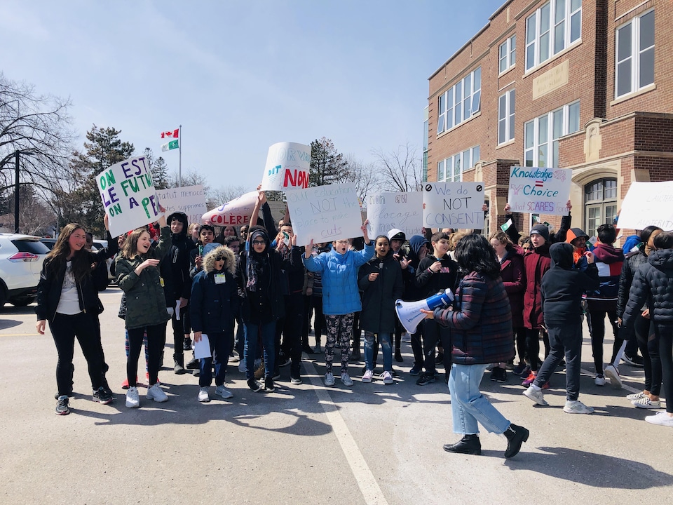 Des élèves brandissent des pancartes lors d'une manifestation devant une école.