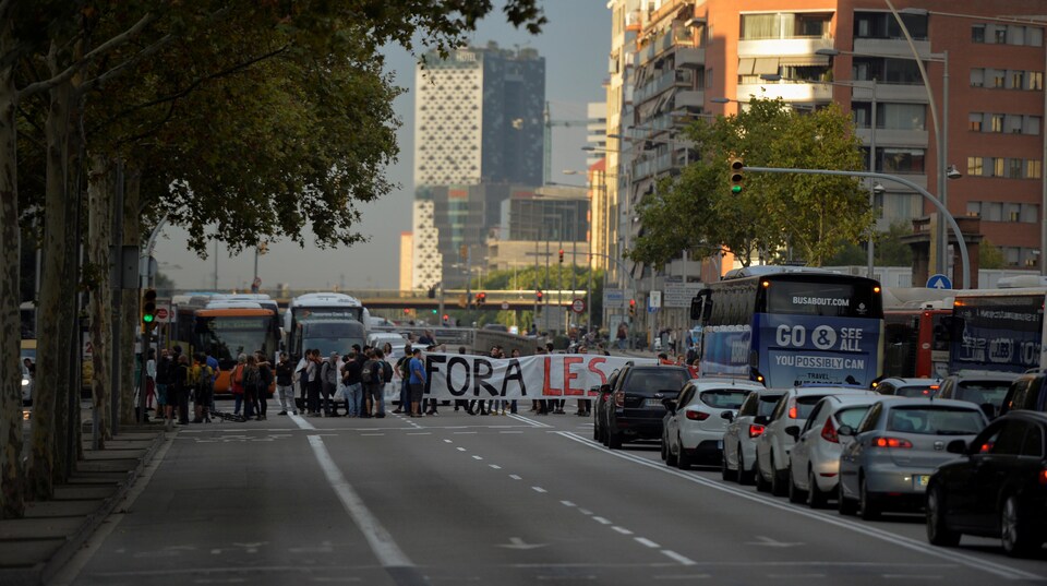 Des manifestants déploient une banderole pour bloquer la circulation sur une artère de Barcelone.