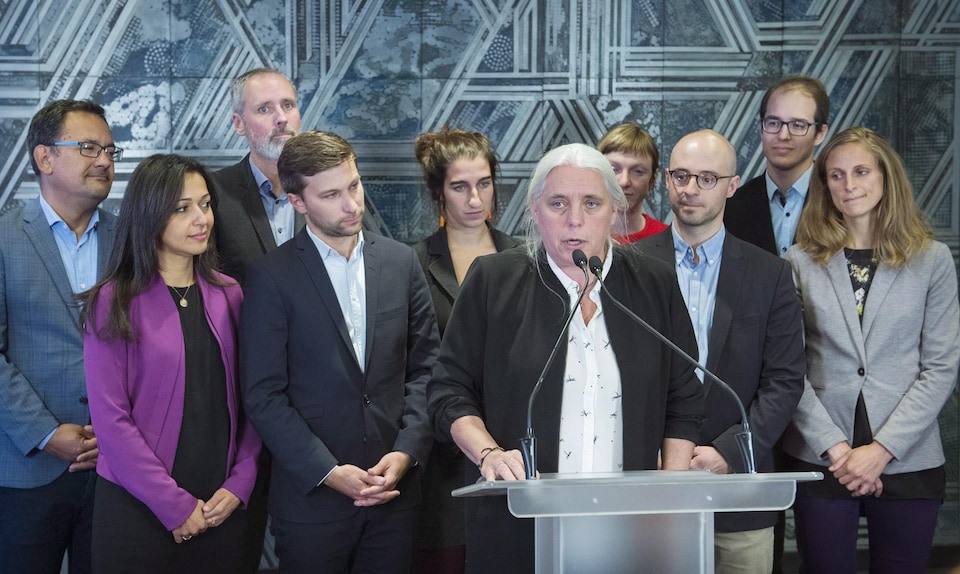 Manon Massé parle en conférence de presse, tout les députés élus de QS se tiennent derrière elle.