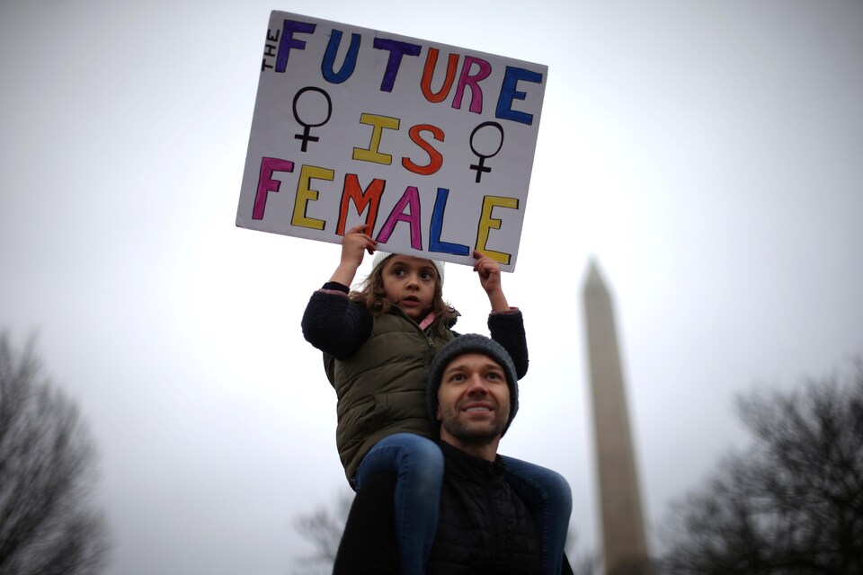 À Washington, une petite fille, sur les épaules de son père, tient une pancarte disant « Le futur est féminin ».