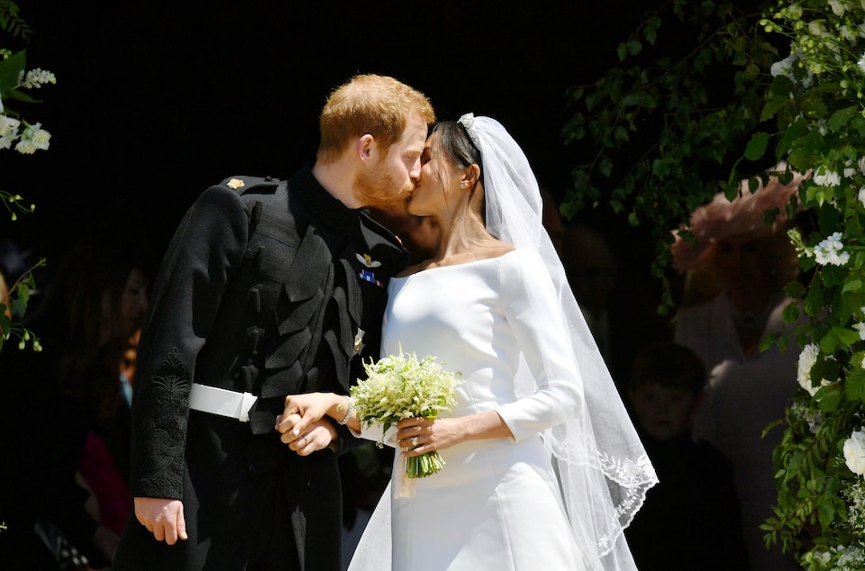 Le couple s'embrasse; la mariée tient un bouquet. 