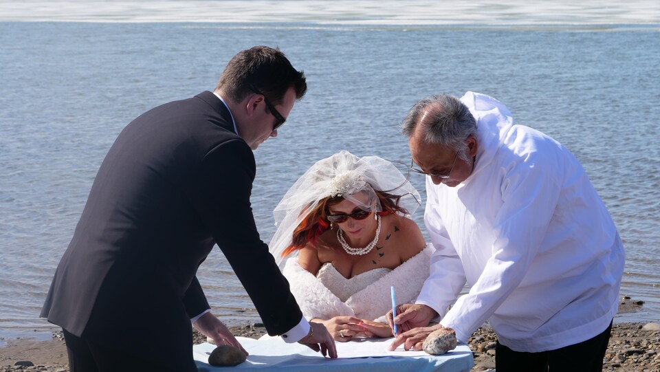 Shawna et Drew Mitchell signent leurs papiers de mariage en compagnie du pasteur. 