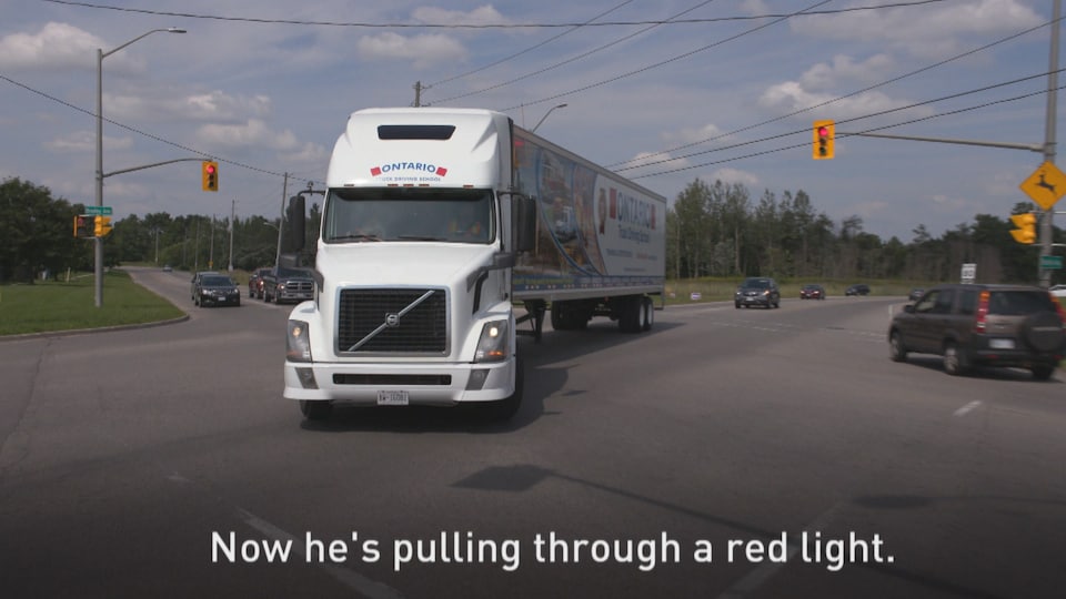 Un camion semi-remorque effectue un virage sur une lumière rouge. 