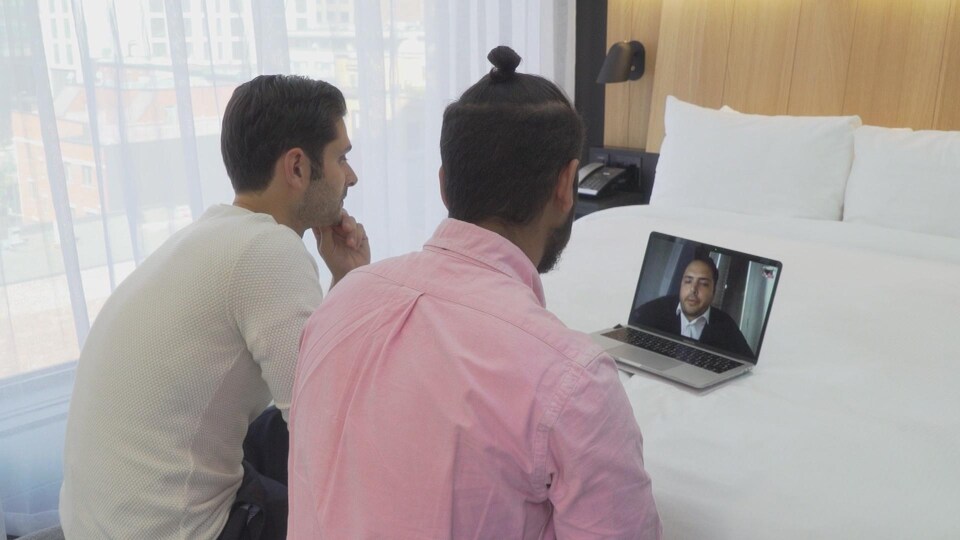 On voit Mauricio et Mario Di Bartolomeo, dans une chambre, qui discutent par vidéoconférence avec leur frère Daniel. 