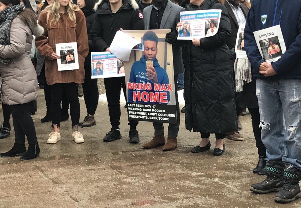 Des gens tiennent des photos et posters de Max, porté disparu le 17 novembre à Regina. 