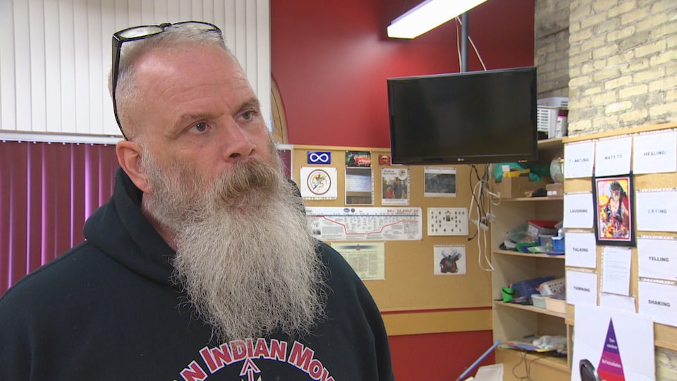 Un homme avec une barbe blanche debout dans un bureau.