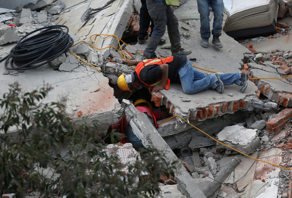 Des secouristes tentent de retrouver des victimes coincées sous les décombres d'un immeuble, à Mexico.