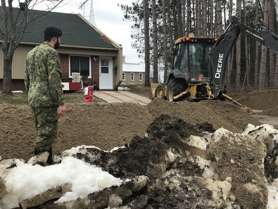 Un soldat canadien supervise des travaux près d'une résidence.