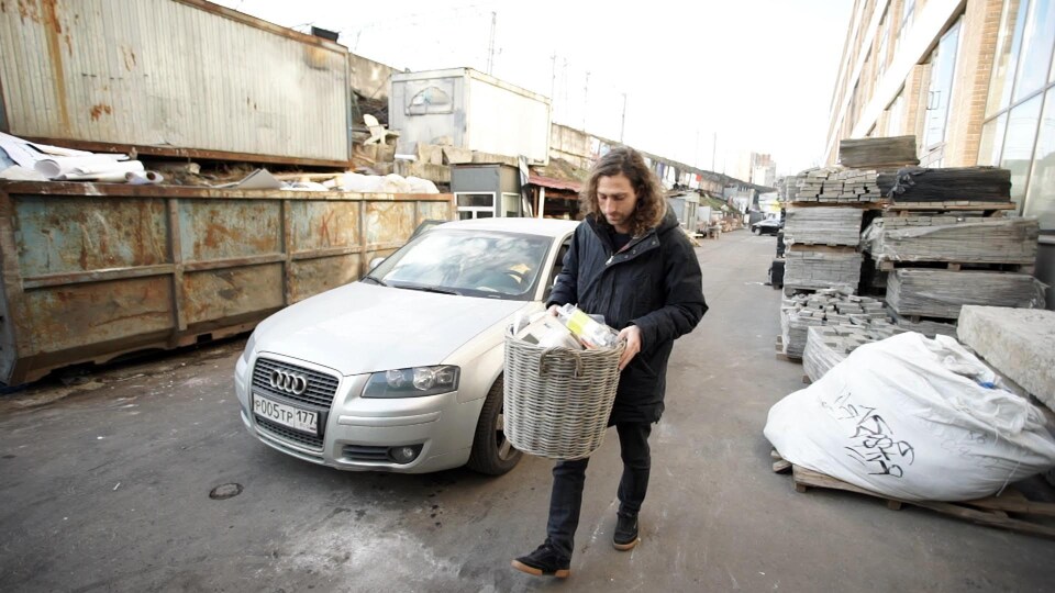 Un homme tient une poubelle dans ses mains.