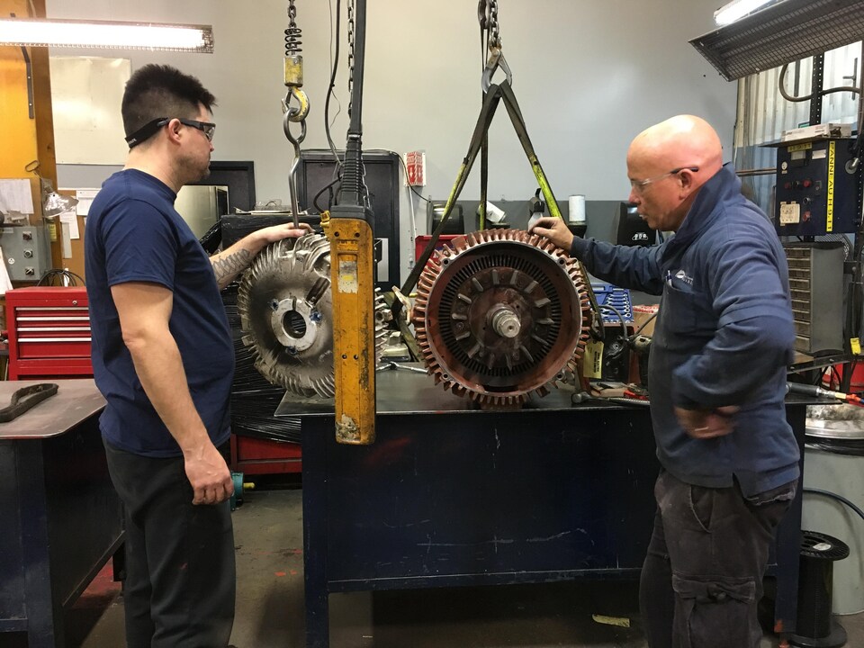 Un homme devant un moteur dans un atelier.