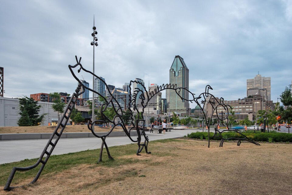 Une partie de la sculpture. Au loin, on voit les gratte-ciel du centre-ville de Montréal.