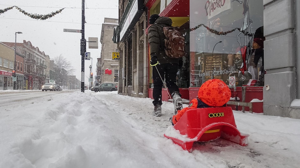 Un parent et son enfant dans un traîneau dans la neige, à Montréal.
