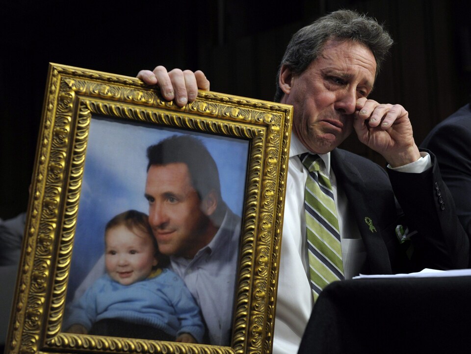 Neil Heslin, en larmes, tient dans ses mains une photo le montrant en compagnie de son fils Jesse.