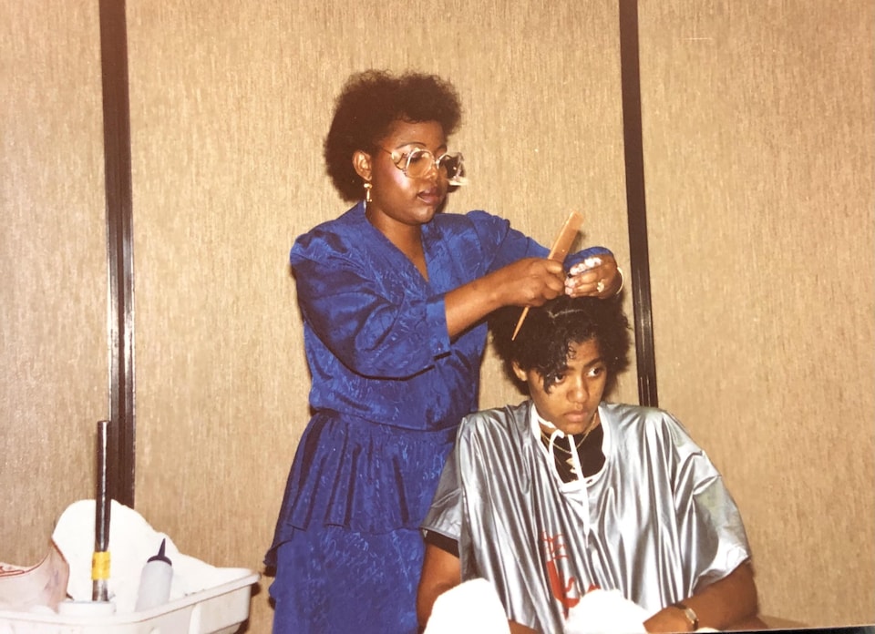 Lola Omoniyi dans son salon qui coiffe une femme.