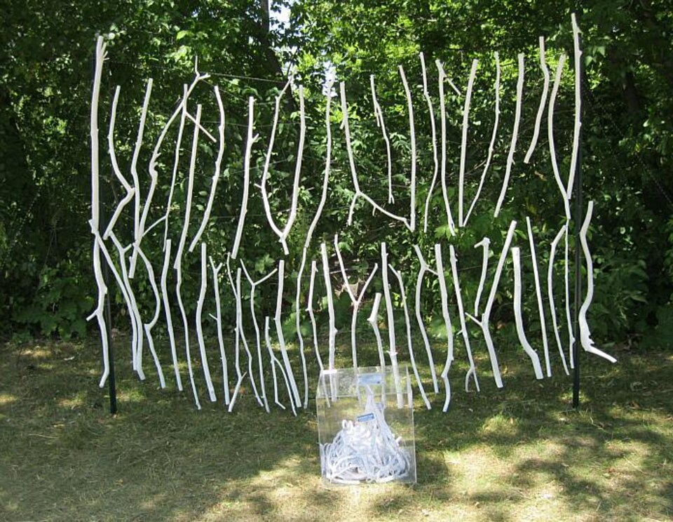 Une oeuvre constituée de deux rangées superposées de branches blanches suspendues.
