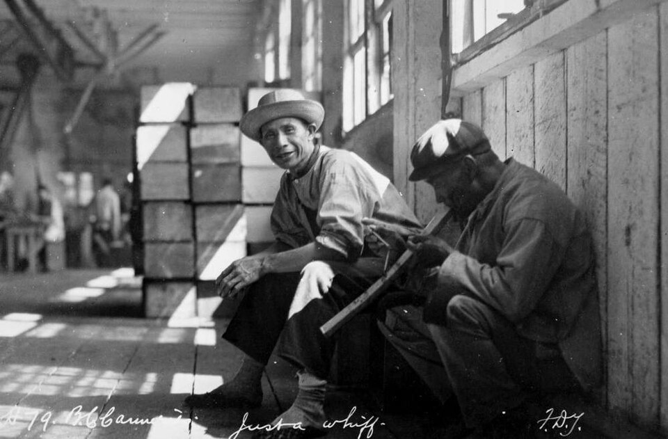 Un homme accroupi fume une pipe remplie d'opium