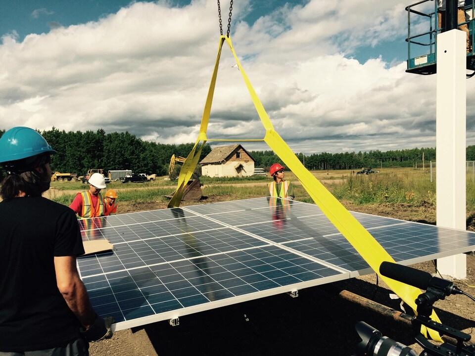 Des membres de la Première Nation Lubicon Lake, en Alberta, aident à l'installation d'un panneau solaire. 