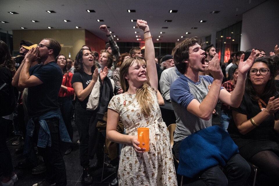 Des jeunes militants lèvent le poing et applaudissent.
