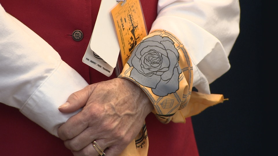 Une bénévole de l'aéroport porte à son poignet un foulard avec une rose, le symbole de la campagne Pas Dans Ma Ville.