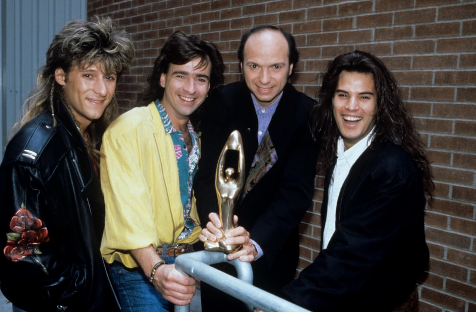 Les membres du groupe Les BB, François Jean, Alain Lapointe et Patrick Bourgeois, en compagnie de l'animateur du Gala de l'Adisq, Michel Rivard, tenant un trophée Félix dans ses mains. C'était en 1990.