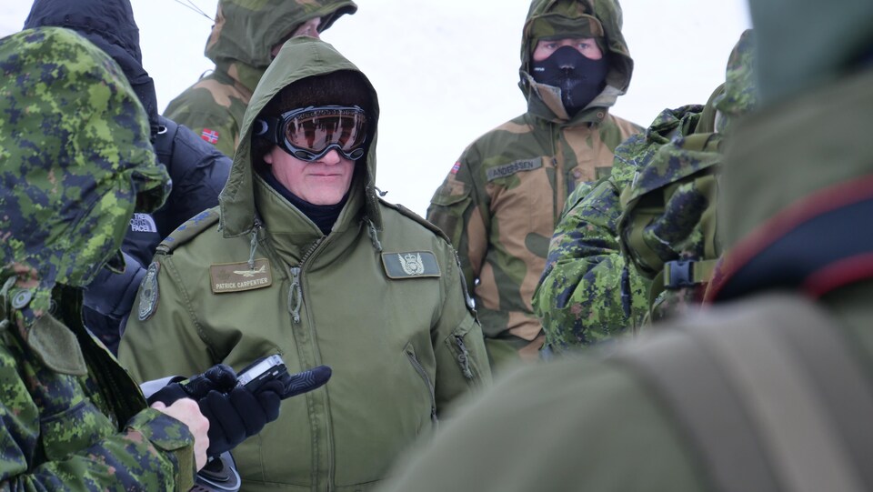 Un militaire portant un manteau et des lunettes de ski. 