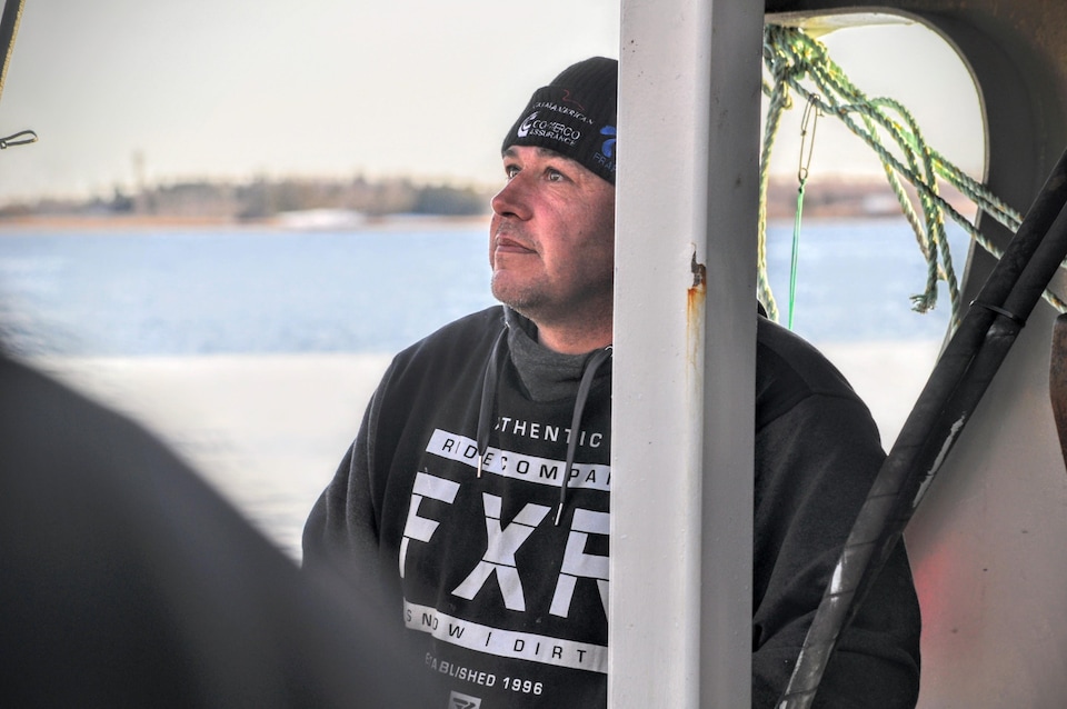 Dean Roussel, avec un regard pensif, debout derrière un pilier de la structure du bateau.