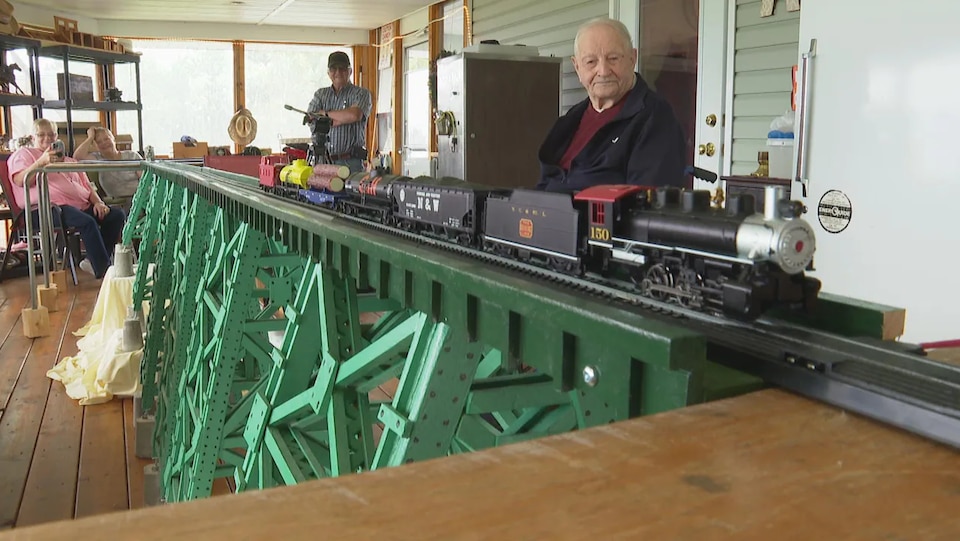 Gunnar et Ray regardent un petit train électrique circuler sur le modèle réduit du pont.