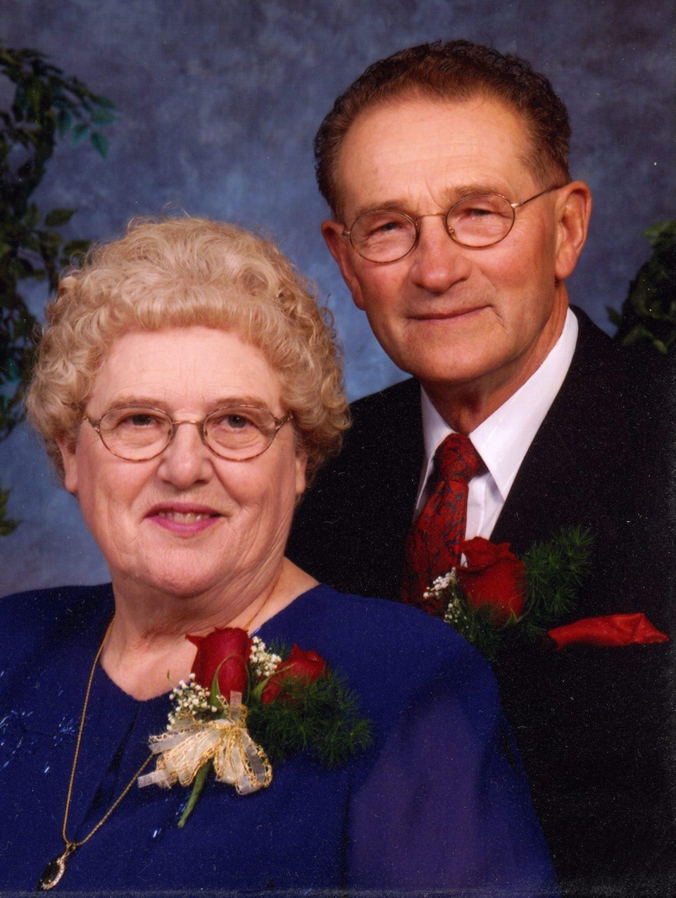 Plan serré de Percy Schmeiser (à droite) et de sa femme Louise. Ils regardent l'objectif en souriant et il porte une rose rouge à la boutonnière.