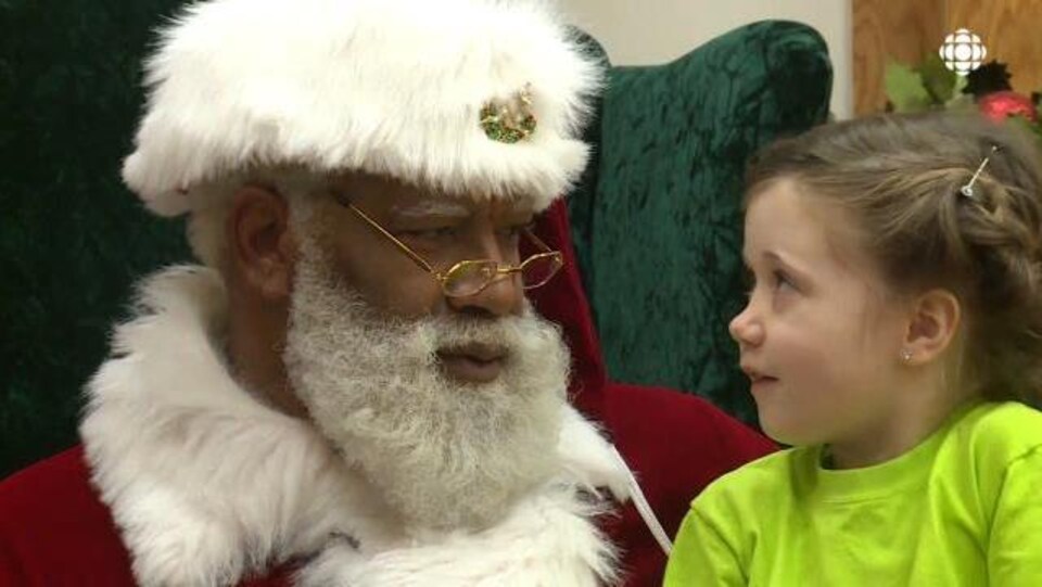 Un père Noël noir s'entretient avec une petite fille. 