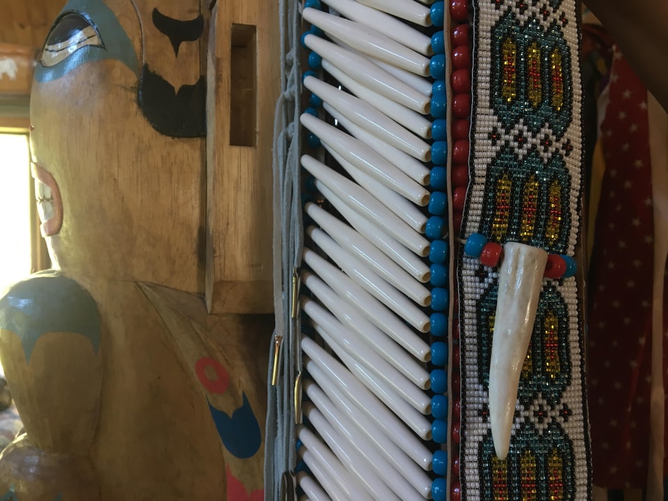 Gros plan sur des perles et une dent qui décorent un habit autochtone traditionnel.
