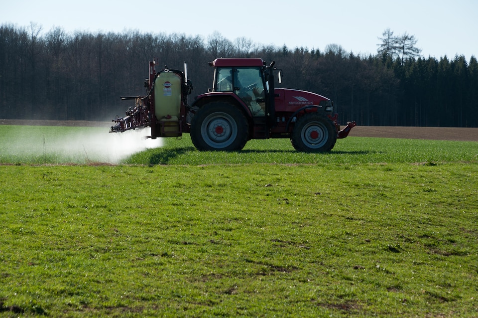 Un agriculteur arrose de pesticides un champ.