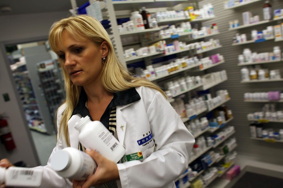 Une pharmacienne à Miami en Floride tient plusieurs bouteilles d'antibiotiques.