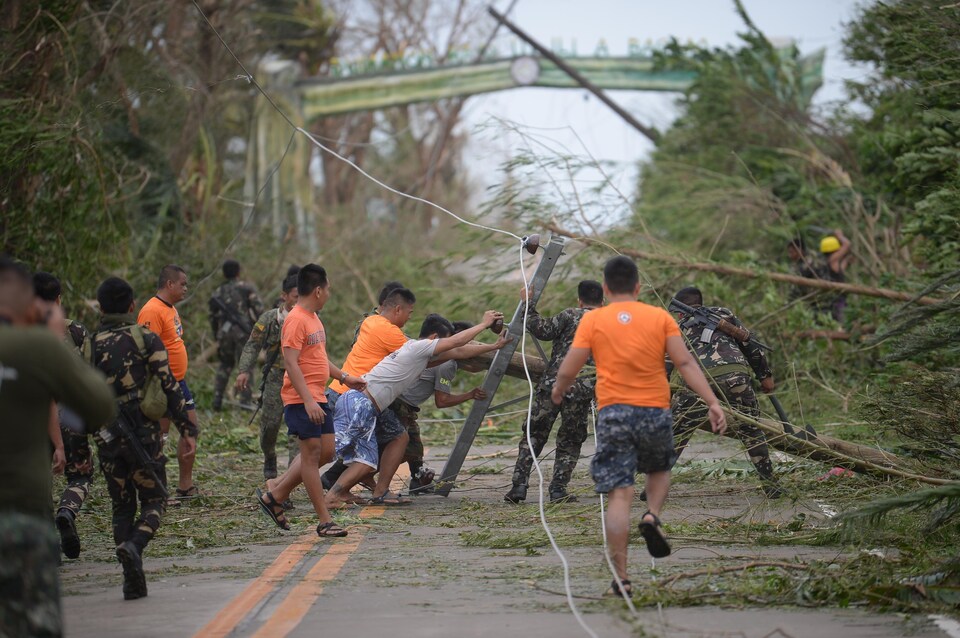 Des secouristes tentent de dégager la route, bloquée par des arbres et des poteaux d'électricité qui sont tombés sous les vents du super typhon Mangkhut.