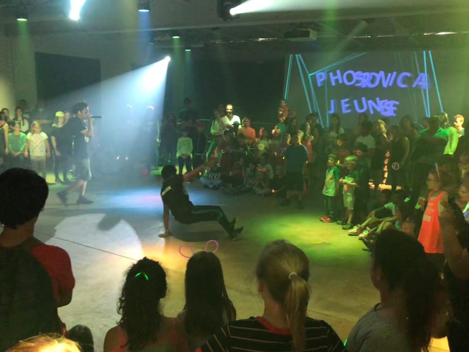 Une personne danse au centre de regroupement de personnes. La foule observe le danseur. 