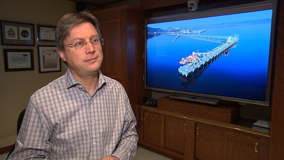 Le PDG du Port de Sept-Îles, Pierre D. Gagnon devant une photo du quai multiusagers local