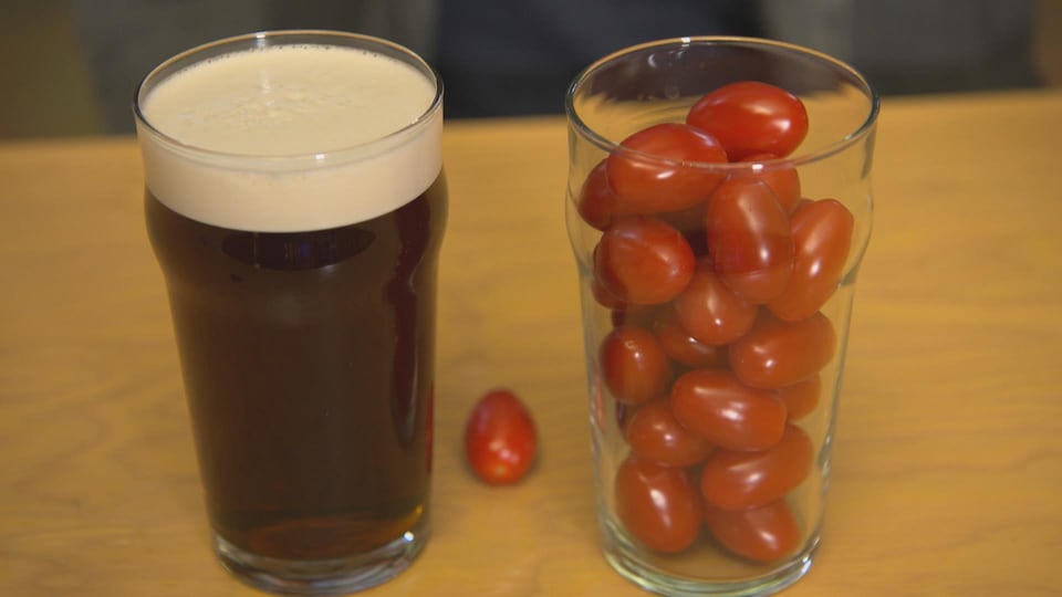 On voit à gauche un verre d'une pinte rempli de bière et à droite un verre d'une pinte rempli de tomates cerises.