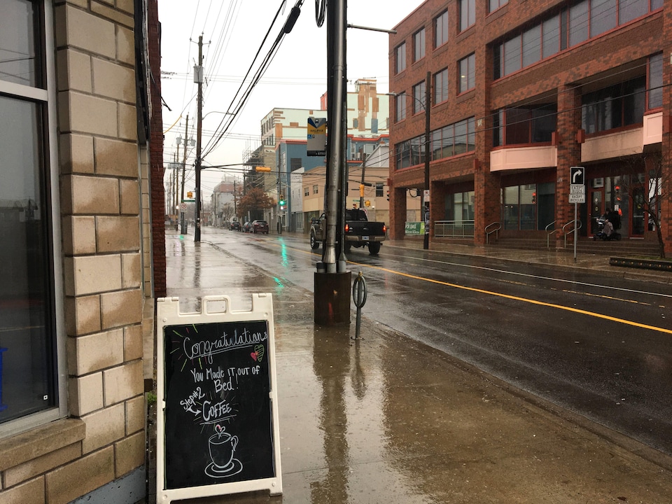 L'enseigne d'un café sur le trottoir sous une forte pluie.